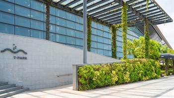 Climber plants cover walls and pillars at the entrance area, softening the edges of the building into the surrounding landscape.